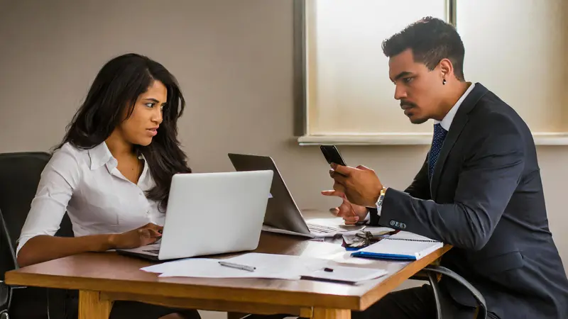 Tense employment severance meeting: Man's focused phone scrutiny hints at heightened tension and possible digital evidence involvement.